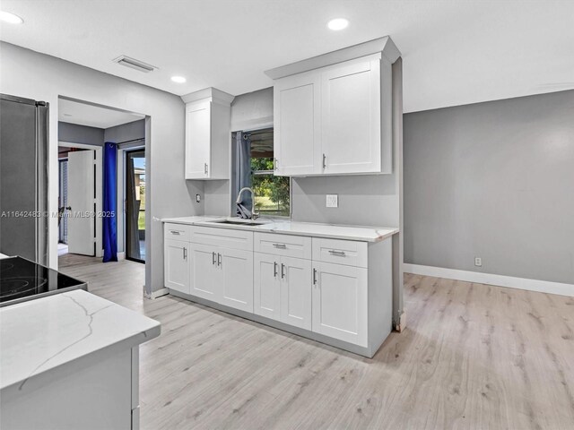 kitchen with stainless steel appliances, white cabinets, and light wood-type flooring