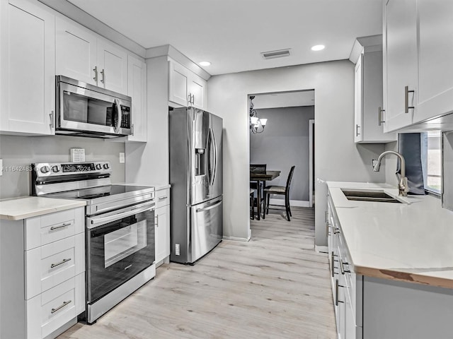 kitchen with sink, light hardwood / wood-style flooring, white cabinetry, and stainless steel appliances