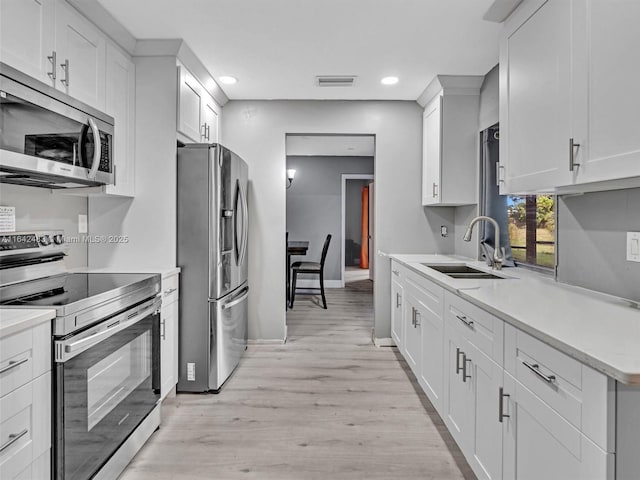 kitchen featuring sink, light wood-type flooring, white cabinets, and appliances with stainless steel finishes