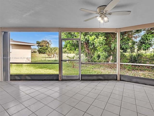 unfurnished sunroom featuring ceiling fan and plenty of natural light