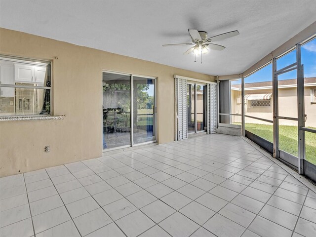 unfurnished sunroom featuring ceiling fan and a wealth of natural light