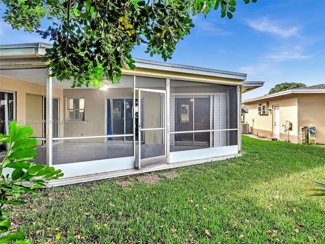 back of property featuring a lawn and a sunroom