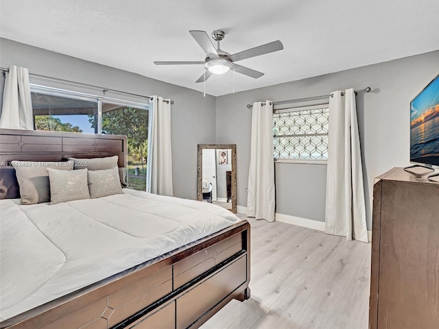 bedroom with ceiling fan, multiple windows, and light wood-type flooring