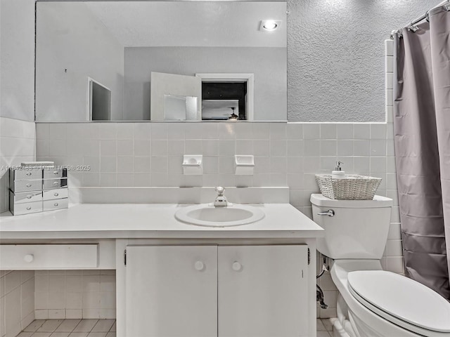 bathroom featuring walk in shower, tile patterned floors, toilet, tile walls, and vanity