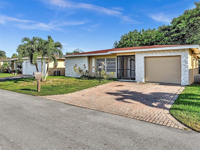 ranch-style house with central air condition unit, a garage, and a front lawn