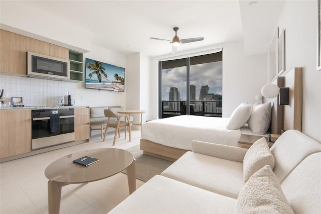 tiled bedroom with ceiling fan, access to outside, and floor to ceiling windows