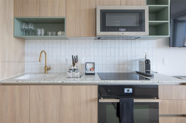 kitchen with sink, decorative backsplash, black appliances, and light stone counters