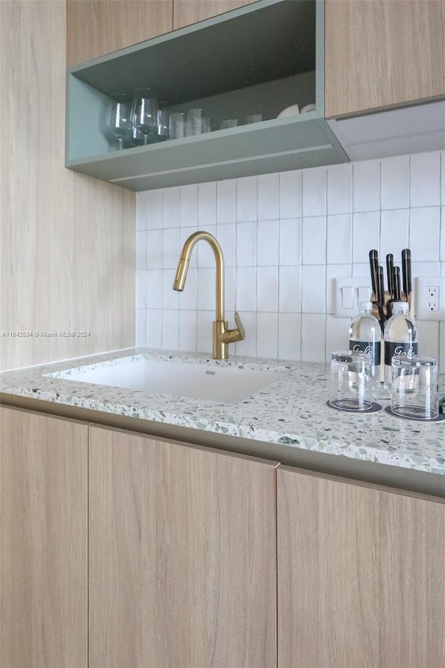 kitchen with sink, light stone counters, light brown cabinetry, and tasteful backsplash