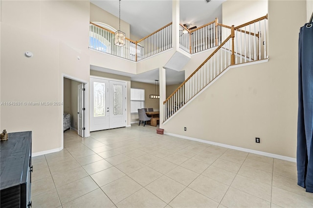 foyer entrance featuring an inviting chandelier, a towering ceiling, french doors, and light tile patterned flooring