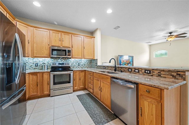 kitchen with appliances with stainless steel finishes, light stone countertops, sink, and kitchen peninsula