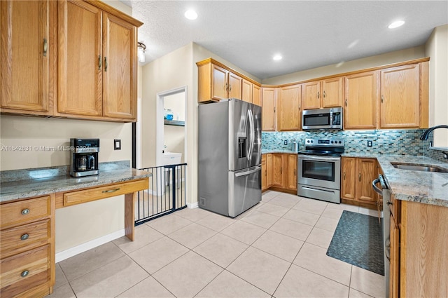 kitchen featuring light tile patterned flooring, appliances with stainless steel finishes, light stone countertops, and sink