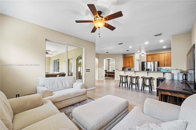 living room featuring ceiling fan, light tile patterned floors, and a textured ceiling