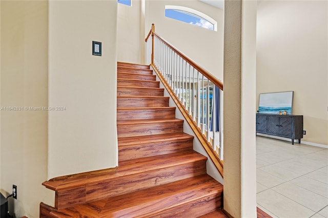 stairs featuring a high ceiling and tile patterned flooring