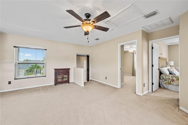 unfurnished bedroom featuring ceiling fan, light carpet, and a textured ceiling