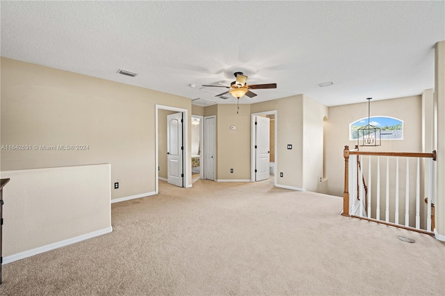 carpeted empty room with ceiling fan and a textured ceiling