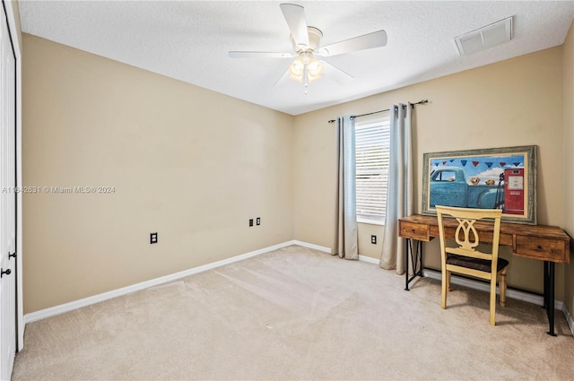 carpeted office space with a textured ceiling and ceiling fan