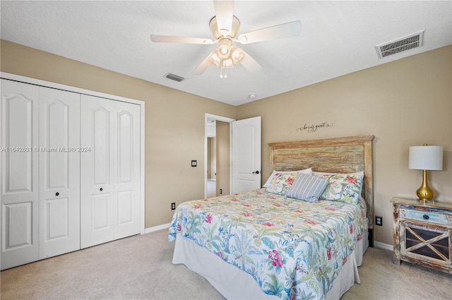 bedroom with light colored carpet, ceiling fan, and a closet