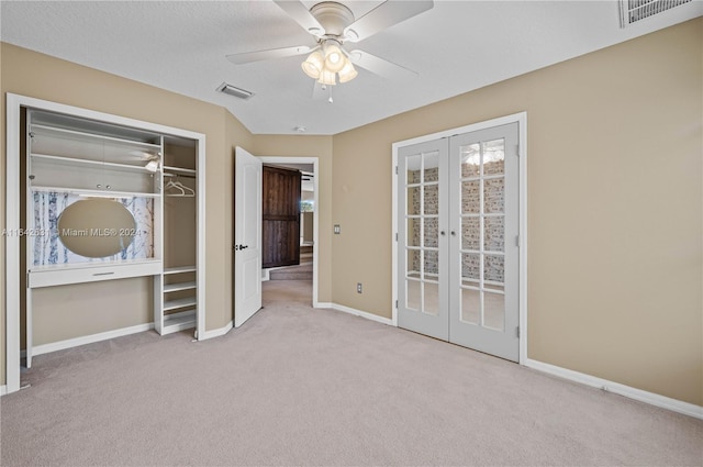 unfurnished bedroom with a closet, light colored carpet, ceiling fan, and french doors