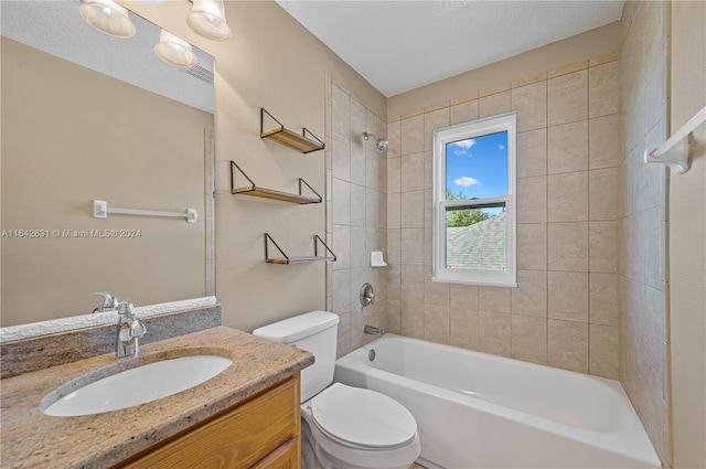 full bathroom with vanity, tiled shower / bath, a textured ceiling, and toilet