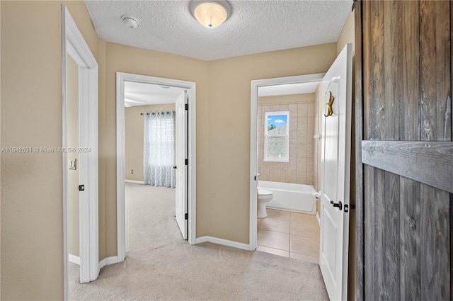 corridor with light carpet and a textured ceiling