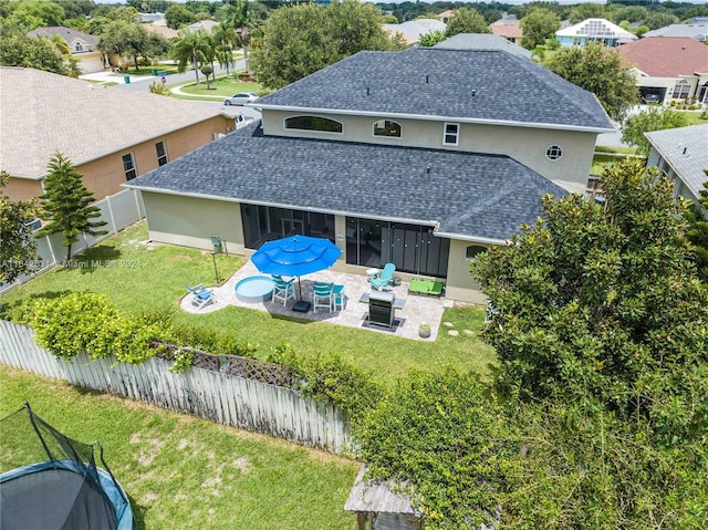 rear view of property featuring a patio, a yard, and an outdoor fire pit