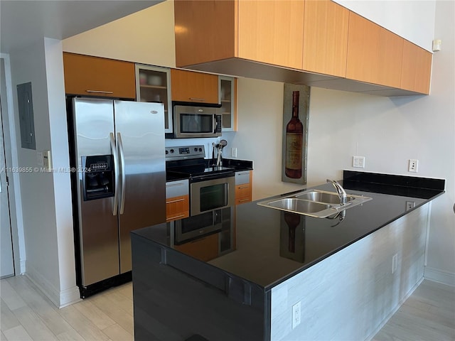 kitchen with sink, stainless steel appliances, kitchen peninsula, and light hardwood / wood-style floors