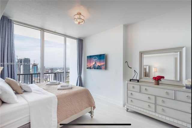 bedroom with access to exterior, floor to ceiling windows, and light hardwood / wood-style floors