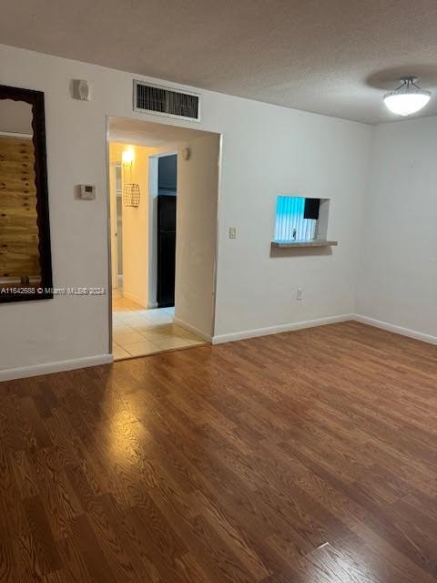 unfurnished room with a textured ceiling and wood-type flooring