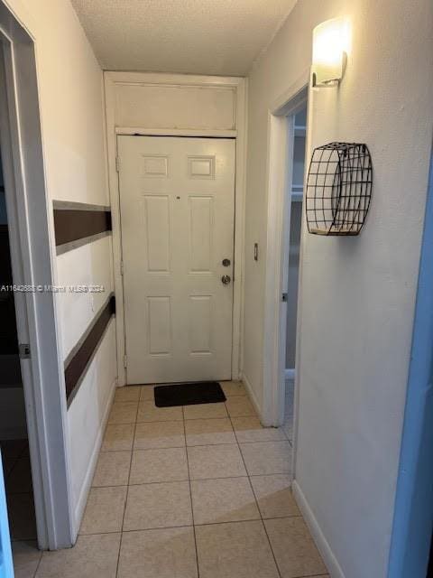 doorway featuring light tile patterned flooring and a textured ceiling