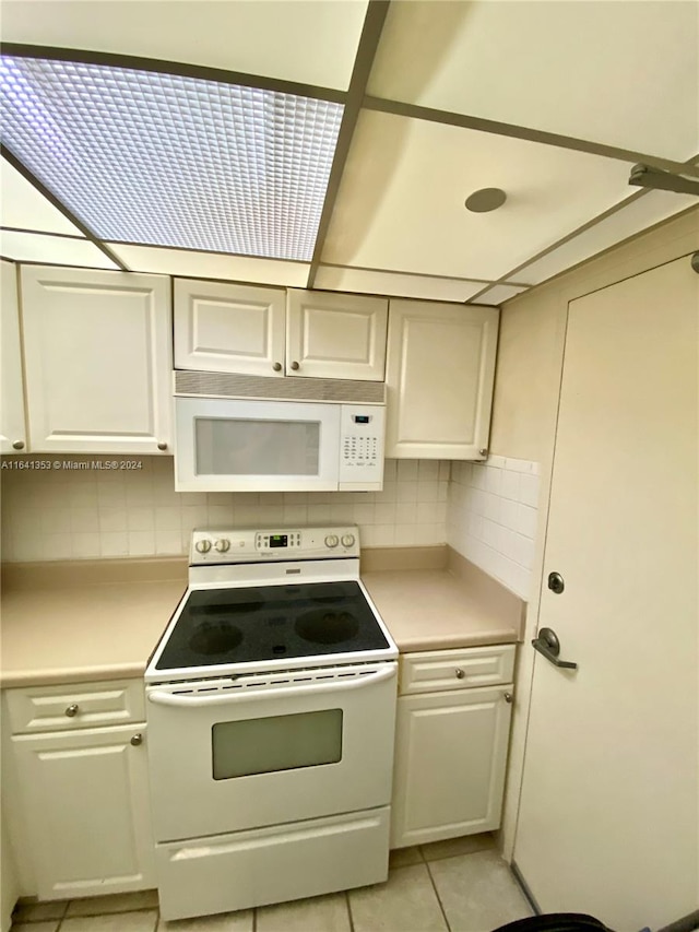 kitchen with backsplash, light tile patterned flooring, and white appliances