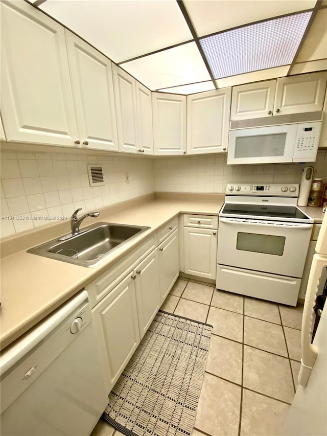 kitchen with sink, white appliances, tasteful backsplash, light tile patterned floors, and white cabinets