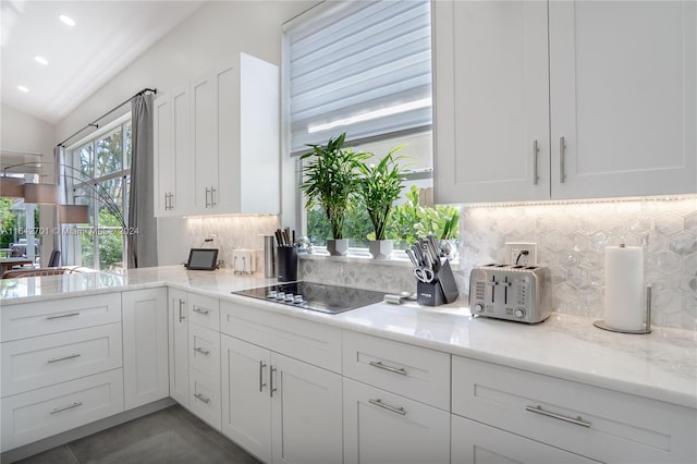 kitchen featuring black electric cooktop, vaulted ceiling, tasteful backsplash, tile patterned flooring, and white cabinetry