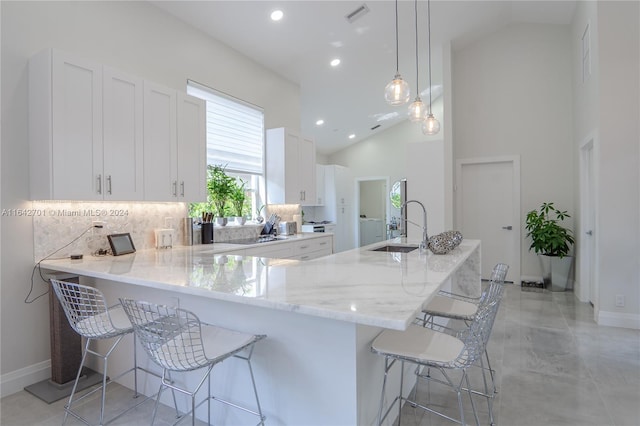 kitchen with backsplash, pendant lighting, white cabinets, light tile patterned floors, and sink