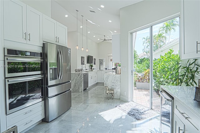 kitchen featuring pendant lighting, beverage cooler, white cabinetry, light stone countertops, and stainless steel appliances