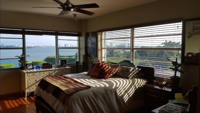 bedroom with ceiling fan, multiple windows, and a water view