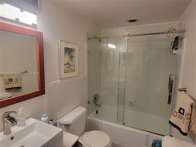 full bathroom featuring toilet, enclosed tub / shower combo, tile walls, and sink