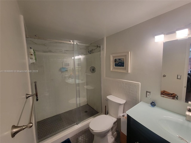 bathroom featuring toilet, tile walls, a shower with door, and vanity