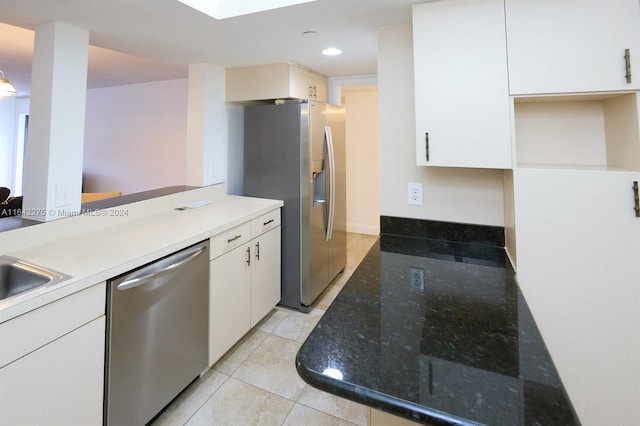 kitchen with light tile patterned floors, stainless steel appliances, white cabinetry, and sink