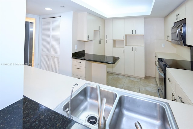 kitchen with appliances with stainless steel finishes, sink, light tile patterned floors, and white cabinets