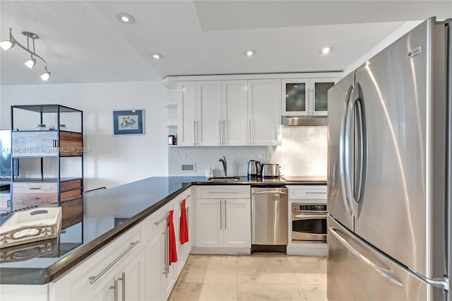 kitchen featuring kitchen peninsula, appliances with stainless steel finishes, white cabinetry, and dark stone countertops