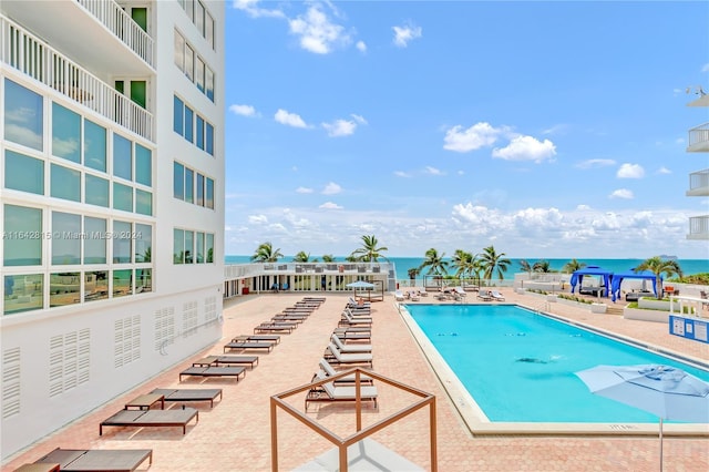 view of swimming pool featuring a water view and a patio