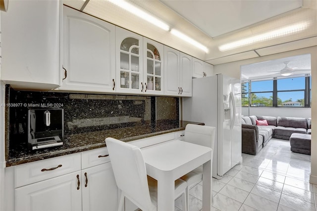 kitchen featuring ceiling fan, decorative backsplash, white refrigerator with ice dispenser, and white cabinetry