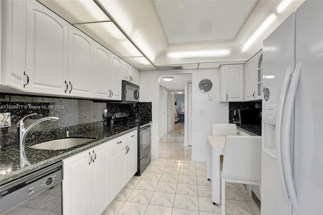 kitchen with white refrigerator with ice dispenser, dishwasher, sink, dark stone countertops, and stainless steel range with electric cooktop