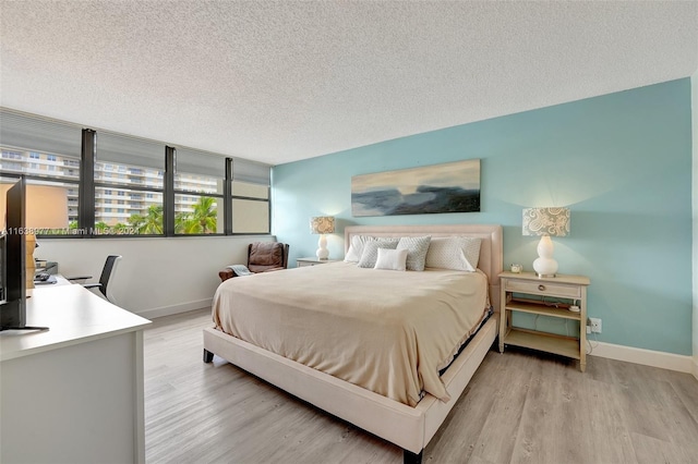 bedroom with a textured ceiling and light hardwood / wood-style flooring