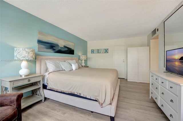 bedroom featuring a textured ceiling and light hardwood / wood-style flooring