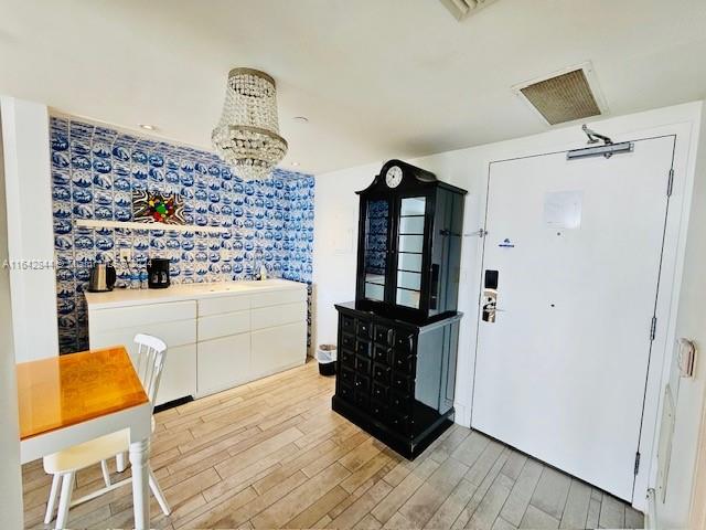 kitchen with light wood-type flooring, a chandelier, and white cabinets