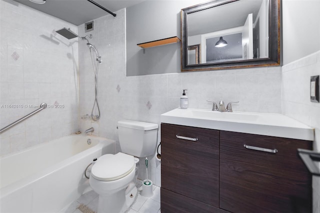 full bathroom featuring toilet, tiled shower / bath, tile walls, vanity, and tile patterned flooring