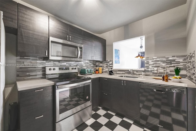 kitchen with hanging light fixtures, sink, appliances with stainless steel finishes, and tasteful backsplash