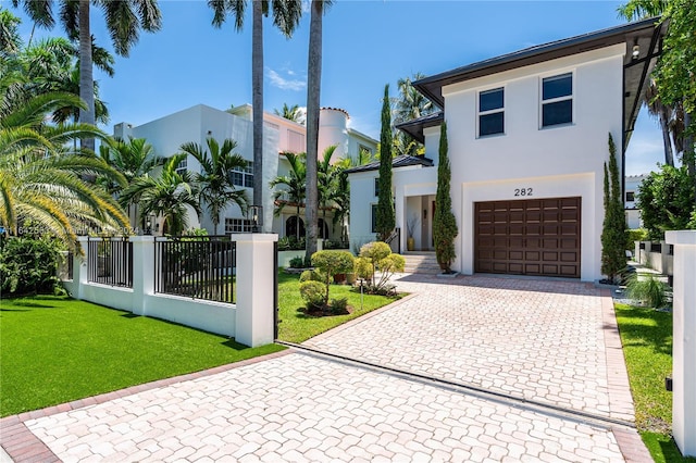 view of front of house featuring a fenced front yard, an attached garage, decorative driveway, stucco siding, and a front yard