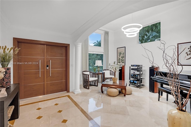 foyer entrance with arched walkways, ornate columns, baseboards, and crown molding